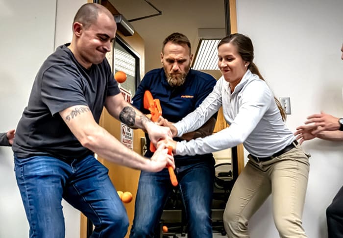 Man holding fake gun being held down by two people on either side.